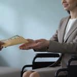 femme en fauteuil roulant recevant enveloppe de paiement