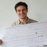 homme souriant brandissant enorme cheque de loterie