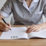 Jeune aide soignante en uniforme remplissant un CV