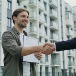 Locataire signe nouveau contrat devant immeuble identique