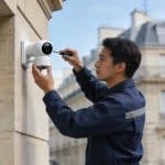technicien installe camera de surveillance connectee immeuble paris