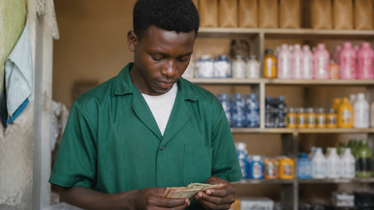 Adolescent en uniforme de travail comptant des billets de banque.