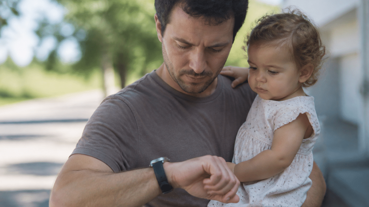 Adulte tenant enfant dans bras, montre chronometre dix heures.