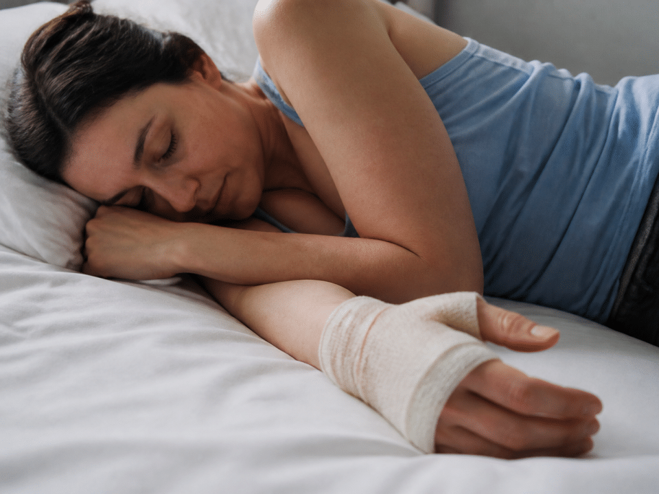 Personne immobilisee main bandee reposant sur lit blanc