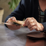 Personne comptant des billets d'euros sur table.
