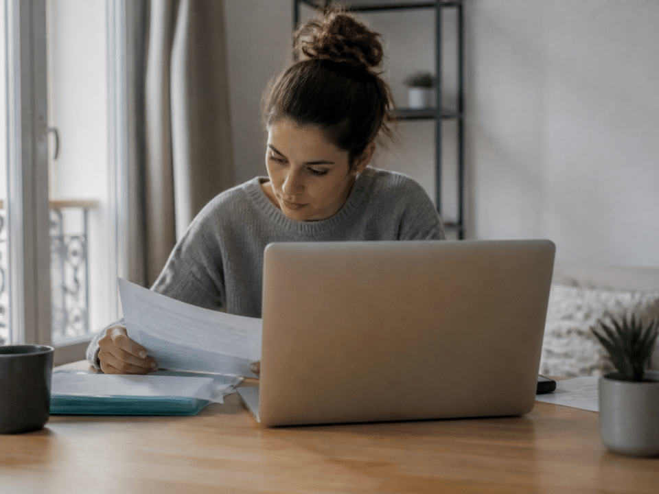 Personne assise devant ordinateur consultant documents administratifs emploi.