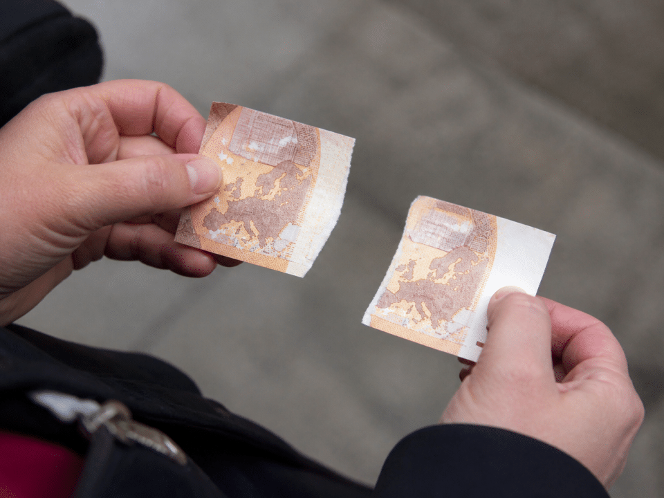 Billet de cinquante euros dechire en deux morceaux.