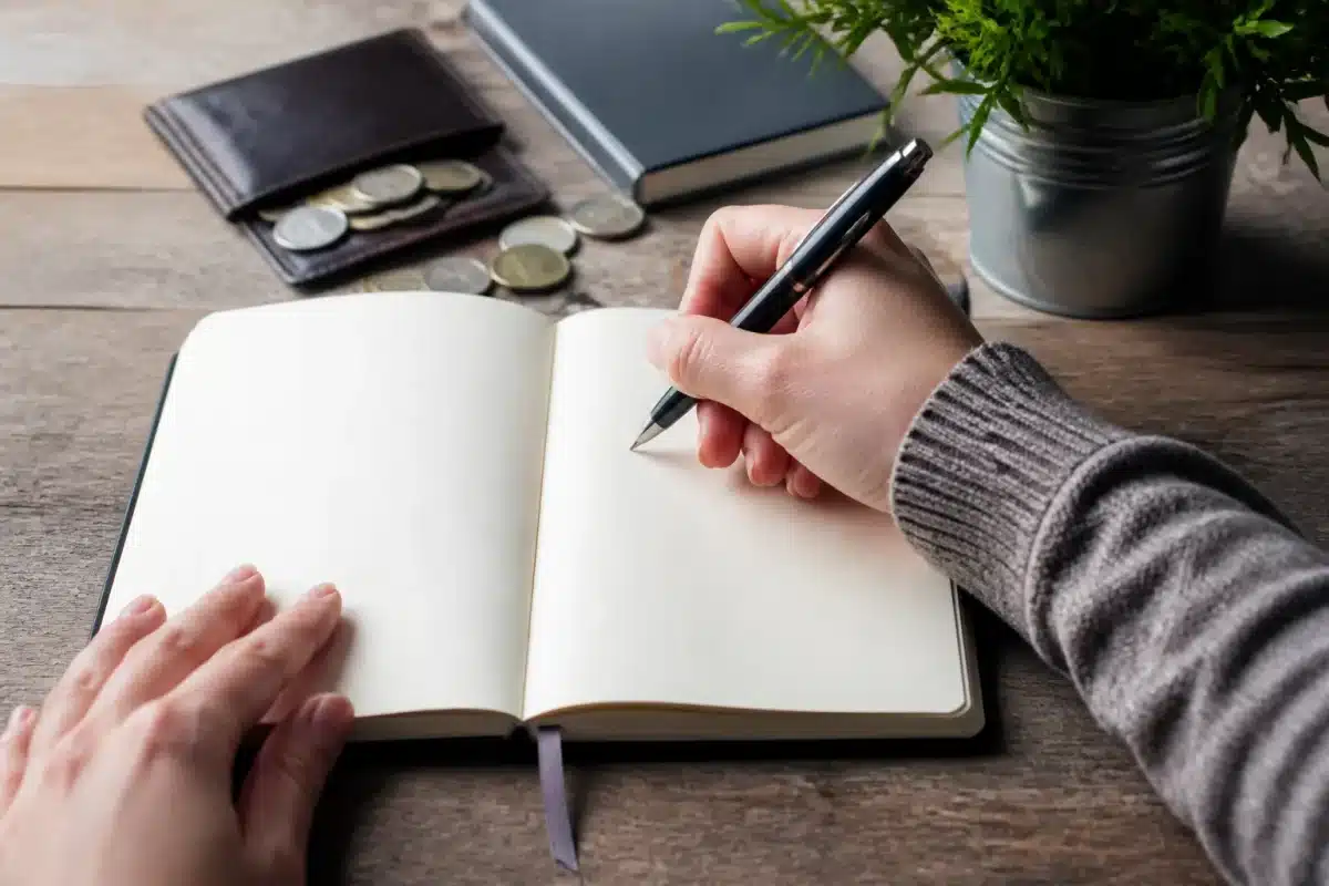 Carnet ouvert avec stylo notant depenses quotidiennes regulieres