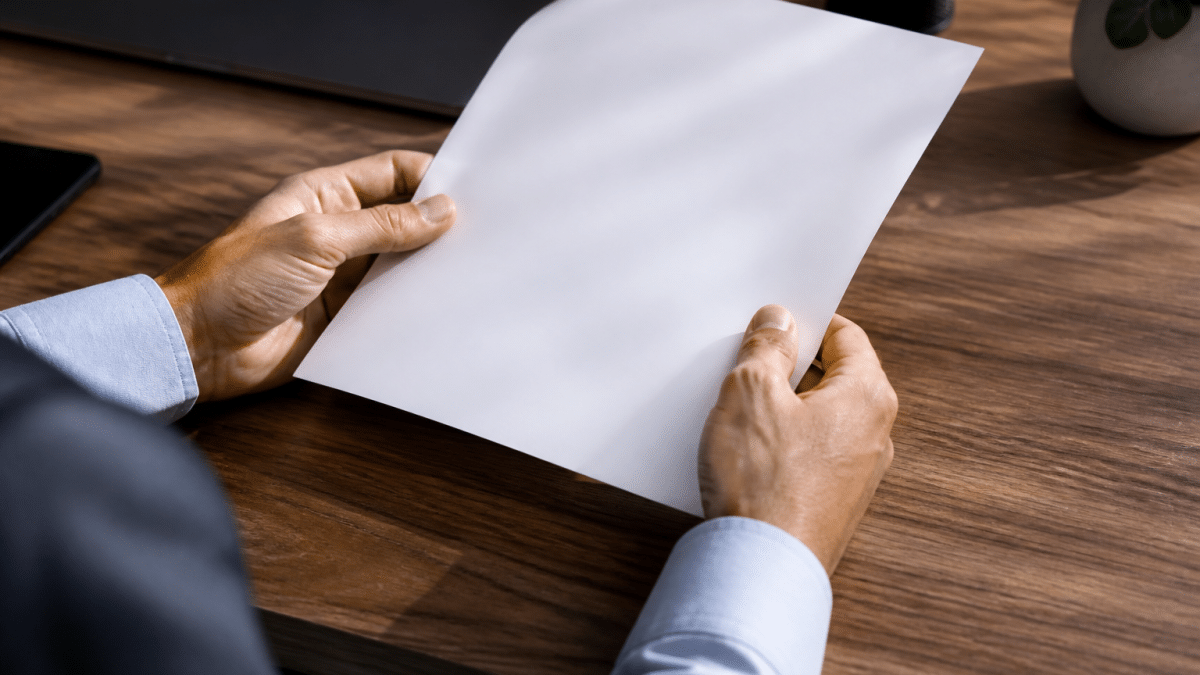 Deux mains tenant un document bancaire sur un bureau