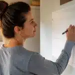 Personne notant dépenses sur calendrier mural, stylo à la main