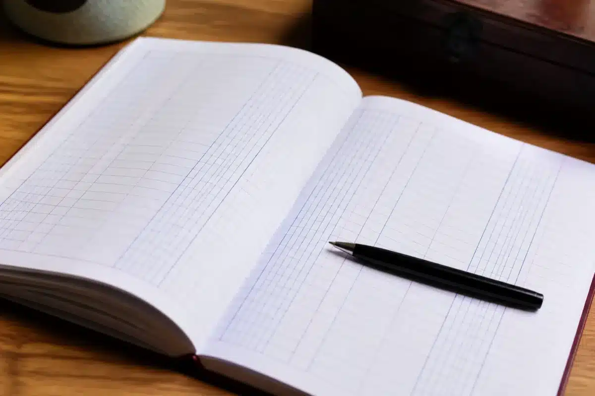 Carnet ouvert avec colonnes de chiffres et stylo noir
