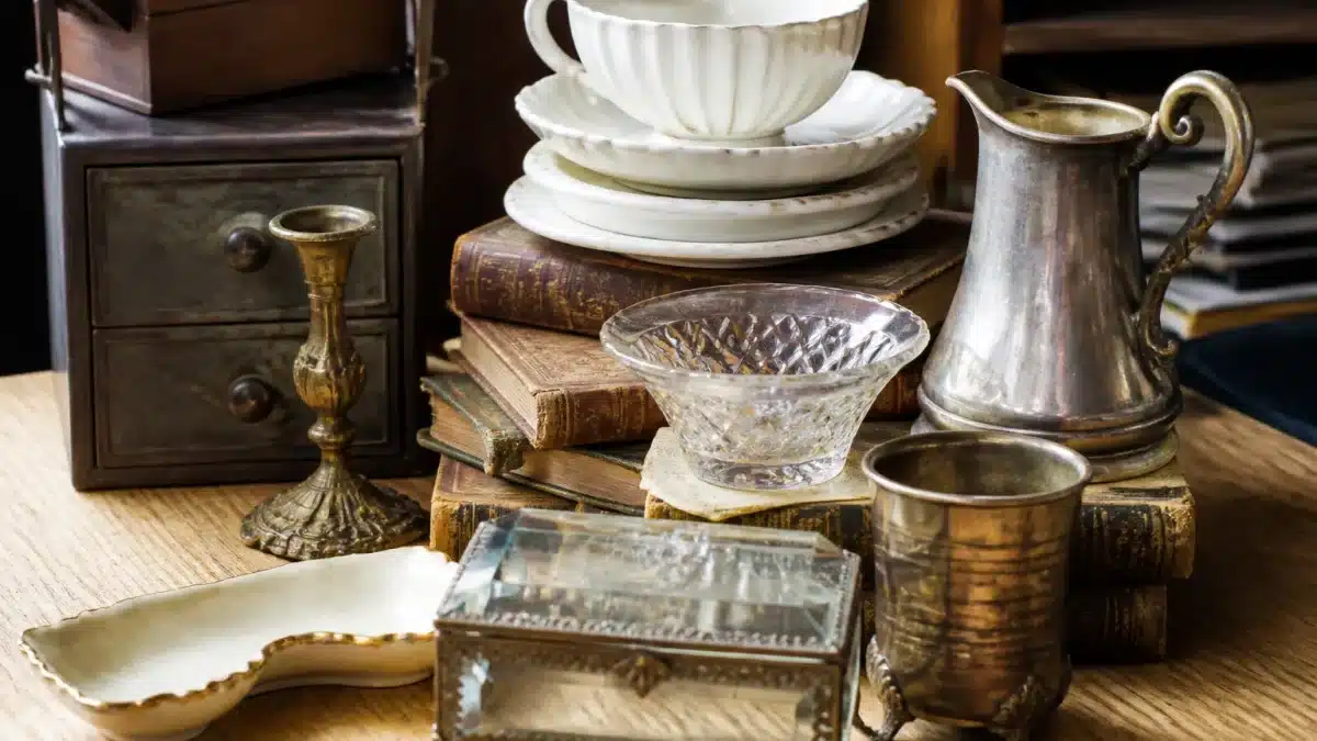 Objets anciens empiles sur table en bois clair