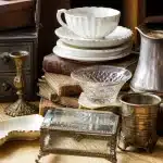 Objets anciens empiles sur table en bois clair