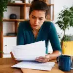 Personne assise consultant document fiscal montrant montants allocation rentrée scolaire
